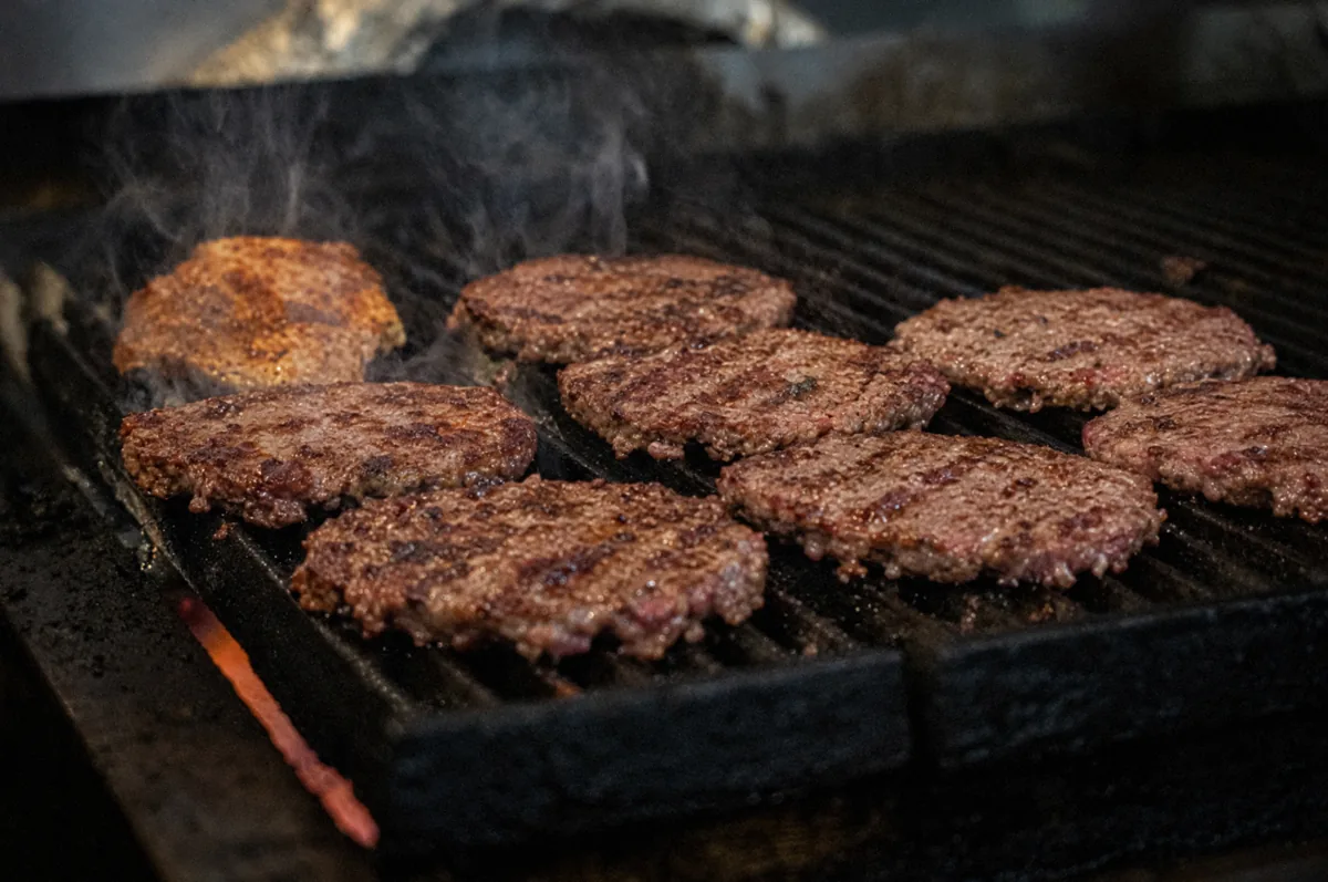 Angus patties searing on the open-flame grill